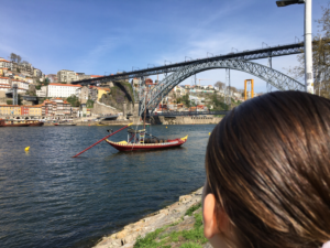 A aluna junto ao rio Douro, olhando para a Ribeira (Porto) com a ponte de D. Luís e o rio Douro em perspetiva.