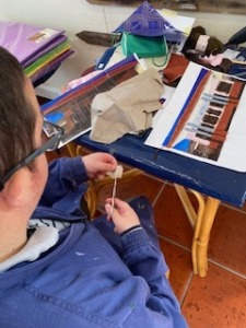 Utente a cortar tecido para colocar no trabalho.
