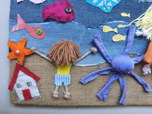Do lado da terra, o menino observa o mar cheio de vida e cor, numa composição onde cada detalhe foi criado com tecidos reutilizados e muita imaginação.