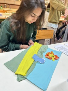 Aluna de 18 anos a coser a paisagem característica da capa do livro.