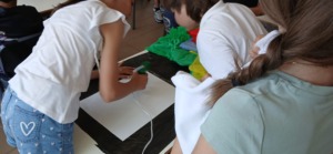 Alunos a colarem tecido branco(fundo) sobre o cartão de um bloco de papel de Cavalinho A3.