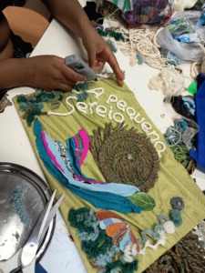 Comprometimento total da aluna com a tarefa de recriar "A Pequena Sereia" em tecido.